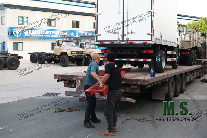 คนงานกำลังติดรถบรรทุกตู้เย็นบนรถเทรลเลอร์เตียงต่ำ 